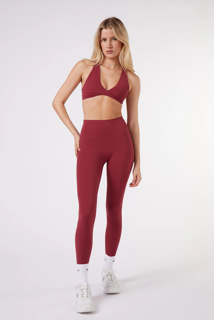 A model showcases red sports bra paired with high-waisted red MUKI yoga pants, exemplifying modern athleisure wear.